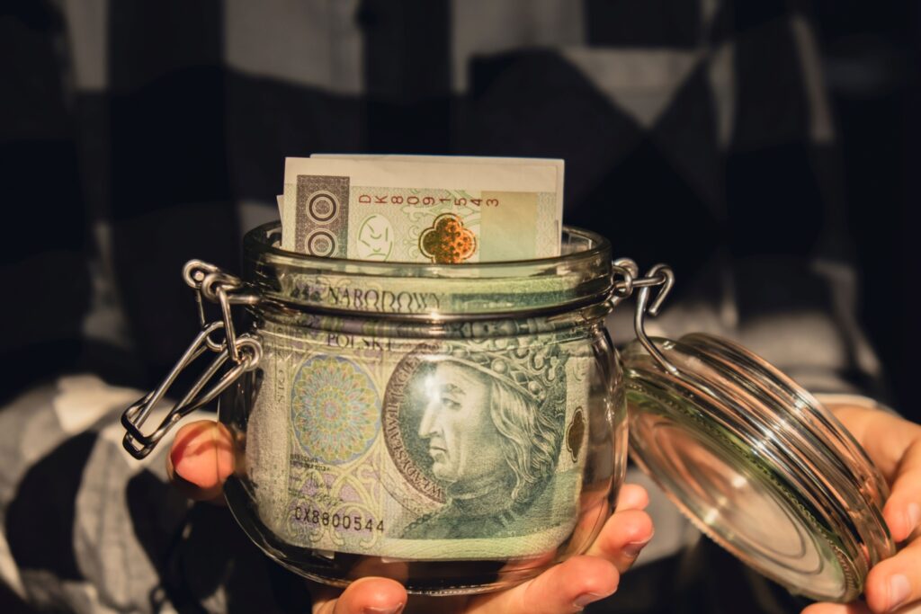 Cédulas de dinheiro em recipiente de vidro indicando a necessidade de uma carteira conservadora com CDBs