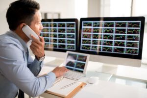 Broker falando com cliente enquanto verifica gráficos de contratos futuros