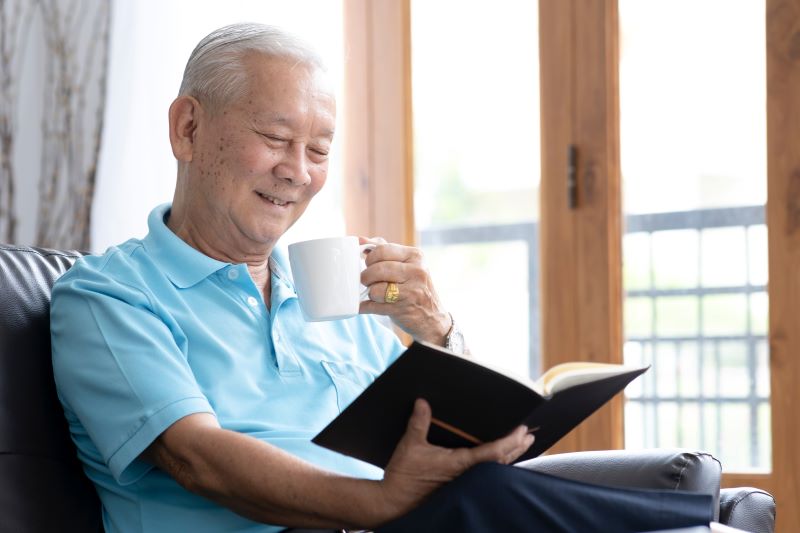 Aposentado aproveitando tempo livre para ler um livro enquanto toma um café