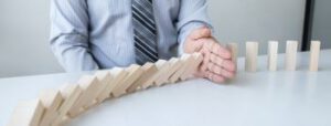 Homem parando fileira de dominós em queda, representando gerência de risco