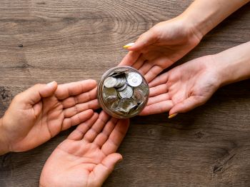 quatro mãos segurando um pote de moedas, representando a transferência da previdência complementar