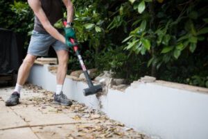 Homem quebrando parede com uma marreta