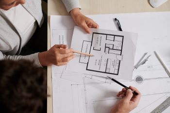 Homens analisando planta-baixa, representando FIIs de papel