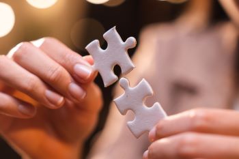 Mãos encaixando duas peças de quebra-cabeça, representando a integração de previdência com planejamento tributário